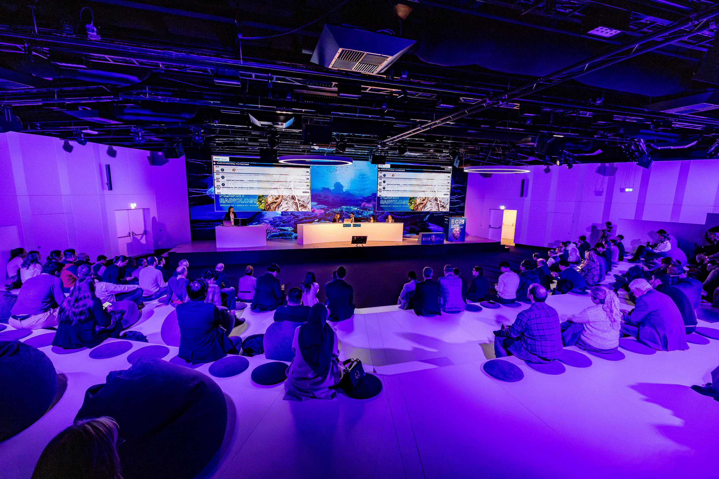 Audience watching a professional conference session with multiple dynamic LED screens and real-time social media integration, showcasing Slidecrew's seamless presentation delivery.