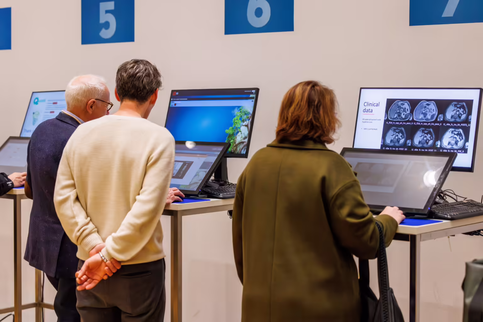 Multiple speakers quickly reviewing their presentations at Slidecrew self-service preview stations during a busy medical conference, ensuring fast, independent preparation before sessions.